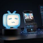 Mascote 3D luminoso da TV azul do Bilibili ao lado de smartphone exibindo aplicativo de streaming com dublagem por inteligência artificial em português