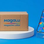 Caixa de entrega com logo do Magazine Luiza e smartphone sobre pedestal azul
