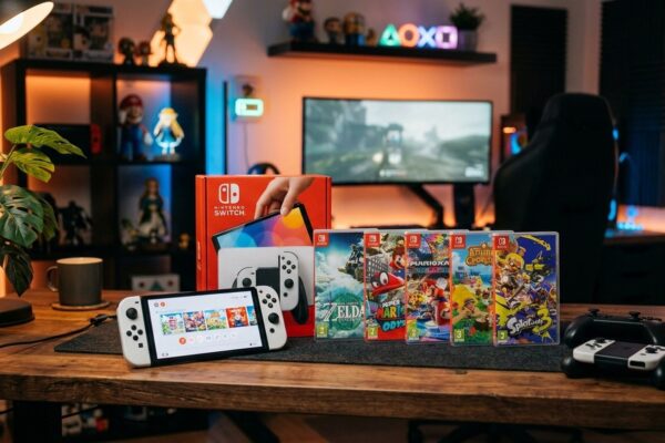 Console Nintendo Switch OLED sobre mesa gamer de madeira com caixas de jogos e iluminação ambiente